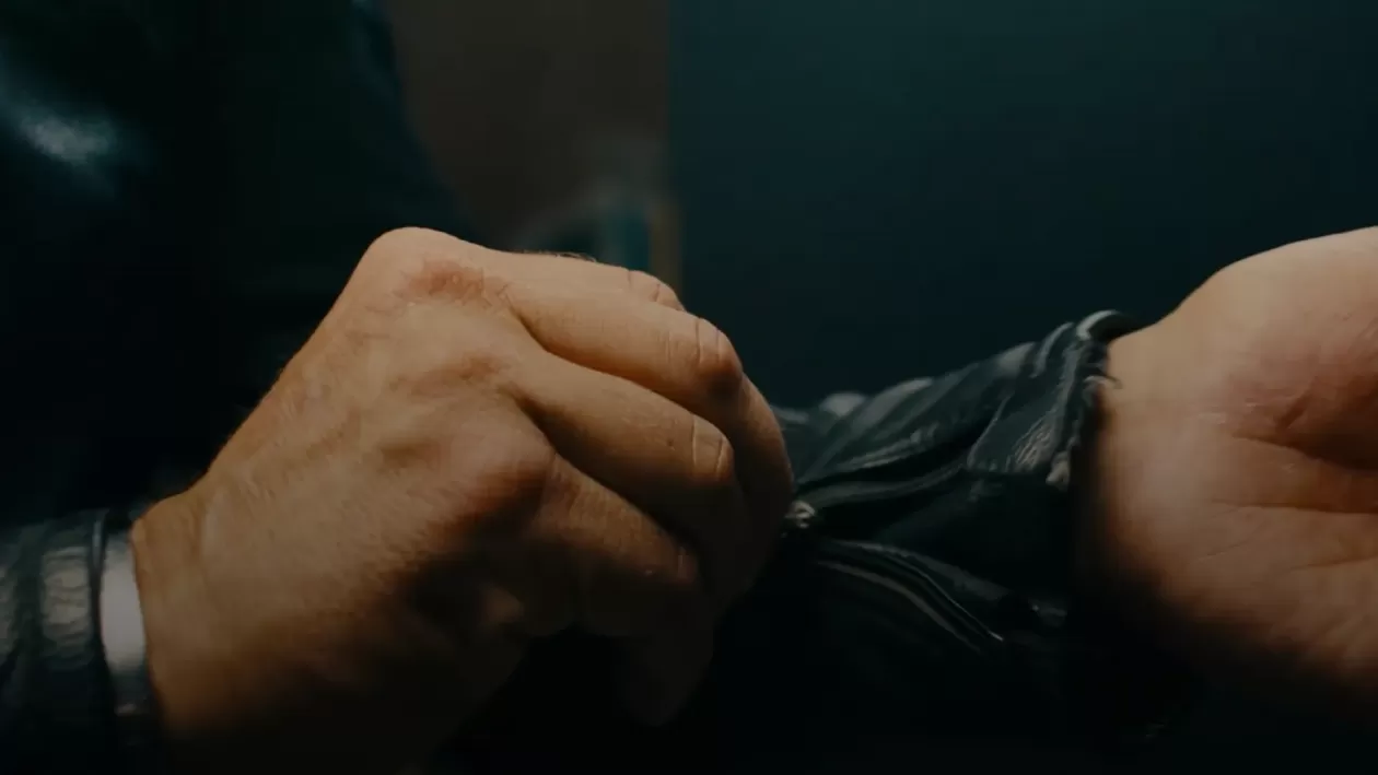 A man zipping up his motorcycle jacket, zoomed in shot of hands